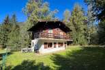 Nestled amidst lush greenery and towering trees, this charming wooden chalet offers a serene mountain retreat.