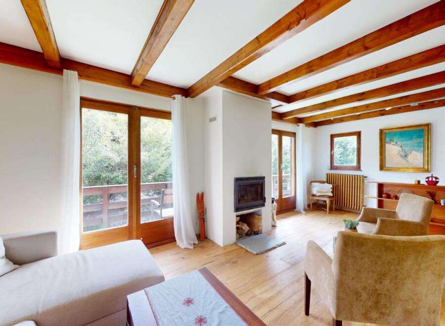 Experience cozy living in this charming room featuring exposed wooden beams and a modern fireplace.