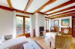 Experience cozy living in this charming room featuring exposed wooden beams and a modern fireplace.