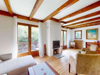 Experience cozy living in this charming room featuring exposed wooden beams and a modern fireplace.