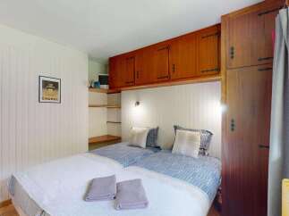 This charming bedroom features two twin beds with stylish blue and white patterned bedding, complemented by plush pillows and soft white blankets.