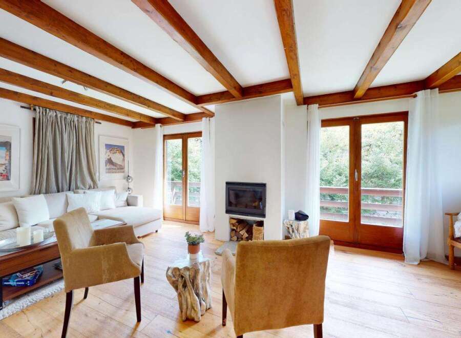 Experience cozy living in this charming living room featuring exposed wooden beams and a welcoming fireplace.