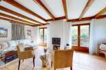 Experience cozy living in this charming living room featuring exposed wooden beams and a welcoming fireplace.