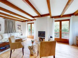 Experience cozy living in this charming living room featuring exposed wooden beams and a welcoming fireplace.