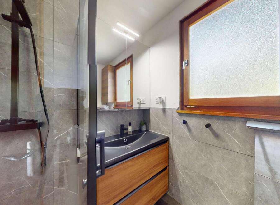 Experience modern luxury in this stunning bathroom featuring a sleek dark sink atop a warm wooden vanity.