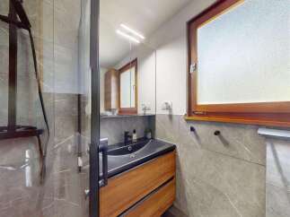 Experience modern luxury in this stunning bathroom featuring a sleek dark sink atop a warm wooden vanity.