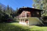 Nestled amidst a lush forest and towering mountains, this charming wooden chalet offers a serene escape.