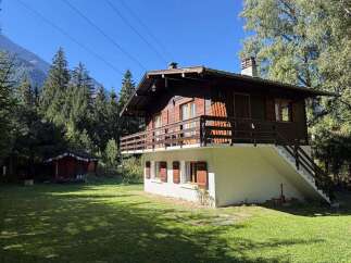 Nestled amidst a lush forest and towering mountains, this charming wooden chalet offers a serene escape.