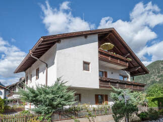 Charming multi-story home with traditional wooden accents and a prominent balcony featuring a yellow umbrella.