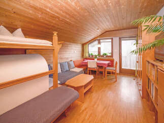 This charming attic apartment features a cozy bunk bed setup and a comfortable L-shaped sofa, perfect for families or groups.