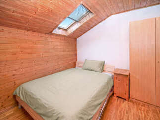 Experience cozy living in this charming attic bedroom, featuring warm wooden paneling on the walls and ceiling.