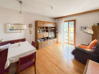 This charming living and dining area features a warm wooden floor and a built-in entertainment unit, perfect for modern living.