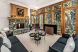 Experience luxurious living in this stunning great room, featuring a magnificent stone fireplace and expansive floor-to-ceiling windows that offer breathtaking views of the surrounding forest.