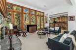 Experience breathtaking natural beauty from this stunning living room, featuring floor-to-ceiling windows that offer panoramic views of the surrounding autumn foliage.