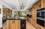 Experience luxury living in this stunning modern kitchen, featuring custom natural wood cabinetry and a sleek black granite countertop.