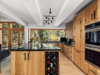 Experience luxury living in this stunning modern kitchen, featuring custom natural wood cabinetry and a sleek black granite countertop.