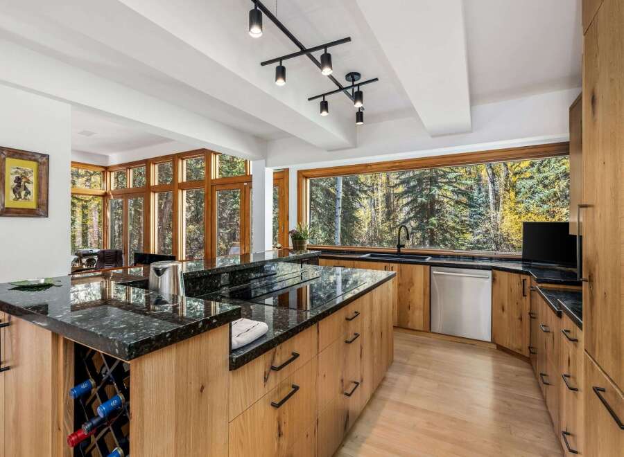 Experience luxury living in this stunning modern kitchen, featuring a large island with a granite countertop and built-in wine rack.