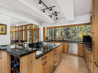 Experience luxury living in this stunning modern kitchen, featuring a large island with a granite countertop and built-in wine rack.