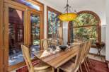 Experience seamless indoor-outdoor living with this elegant dining room, featuring expansive wooden-framed glass doors that open to a serene, stone-paved patio and lush greenery.