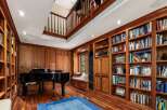 Step into this luxurious library, featuring rich wood paneling and floor-to-ceiling bookshelves filled with a diverse collection.