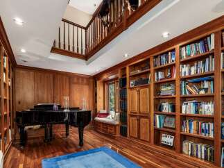 Step into this luxurious library, featuring rich wood paneling and floor-to-ceiling bookshelves filled with a diverse collection.