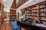 This luxurious living room features a grand piano, a cozy fireplace, and extensive built-in bookshelves, creating an elegant and inviting atmosphere.