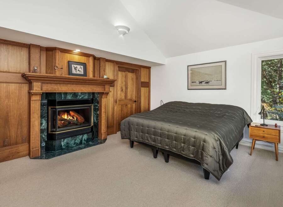 Cozy up by the fireplace in this inviting bedroom, featuring a beautiful wooden mantel and a striking green marble surround.