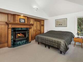 Cozy up by the fireplace in this inviting bedroom, featuring a beautiful wooden mantel and a striking green marble surround.