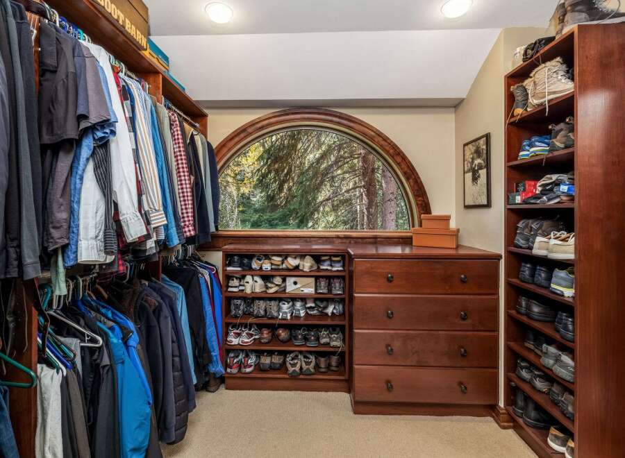 Discover organized luxury in this spacious walk-in closet, featuring ample hanging space for your wardrobe and extensive shelving dedicated to shoe storage.
