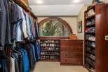 Discover organized luxury in this spacious walk-in closet, featuring ample hanging space for your wardrobe and extensive shelving dedicated to shoe storage.