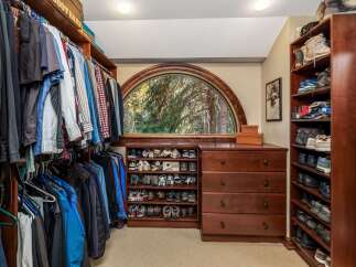 Discover organized luxury in this spacious walk-in closet, featuring ample hanging space for your wardrobe and extensive shelving dedicated to shoe storage.