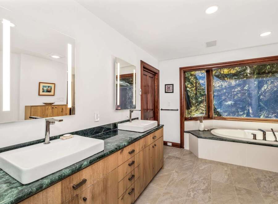Experience luxury in this stunning bathroom featuring a spacious double vanity with vessel sinks and sleek green marble countertops.