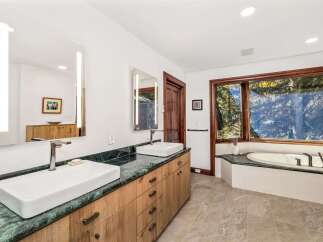 Experience luxury in this stunning bathroom featuring a spacious double vanity with vessel sinks and sleek green marble countertops.