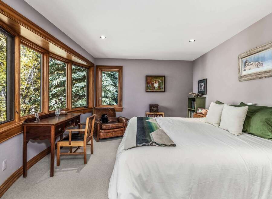 This charming bedroom features a large bay window offering serene views of the surrounding trees, perfect for a peaceful retreat.