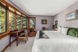 This charming bedroom features a large bay window offering serene views of the surrounding trees, perfect for a peaceful retreat.