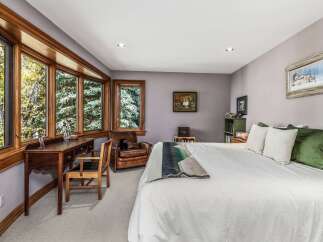 This charming bedroom features a large bay window offering serene views of the surrounding trees, perfect for a peaceful retreat.