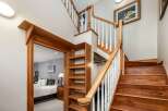 Ascend to the upper level via a beautifully crafted wooden staircase, featuring white balusters and a warm wood handrail.