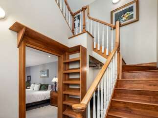 Ascend to the upper level via a beautifully crafted wooden staircase, featuring white balusters and a warm wood handrail.