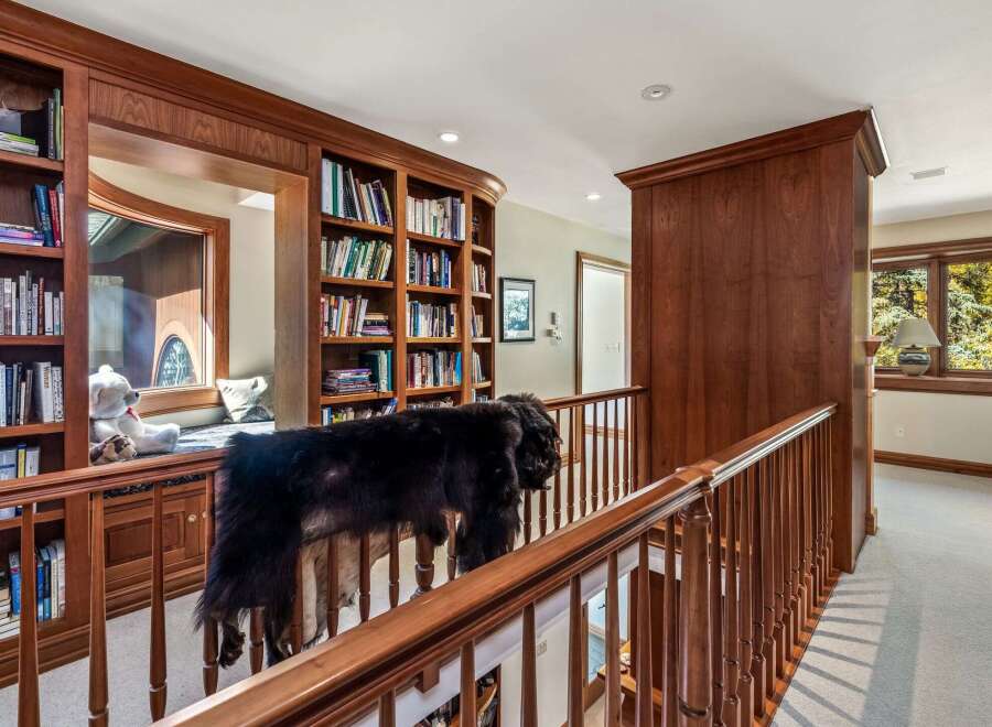 This spacious hallway features elegant custom wood cabinetry and built-in bookshelves, offering ample storage and a sophisticated aesthetic.