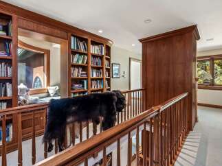 This spacious hallway features elegant custom wood cabinetry and built-in bookshelves, offering ample storage and a sophisticated aesthetic.