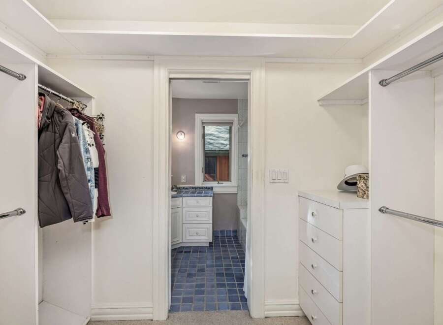 Step into this spacious walk-in closet, offering ample storage with multiple hanging rods and a convenient chest of drawers.