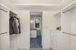 Step into this spacious walk-in closet, offering ample storage with multiple hanging rods and a convenient chest of drawers.