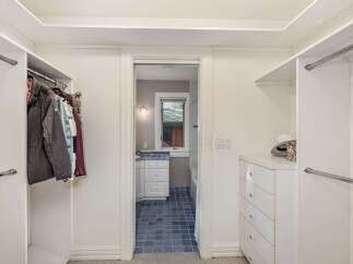 Step into this spacious walk-in closet, offering ample storage with multiple hanging rods and a convenient chest of drawers.