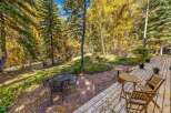 Enjoy the vibrant autumn colors from this charming outdoor living space, featuring a spacious wooden deck and a stone patio perfect for al fresco dining.