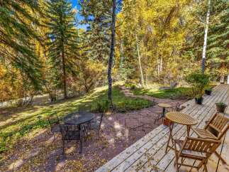 Enjoy the vibrant autumn colors from this charming outdoor living space, featuring a spacious wooden deck and a stone patio perfect for al fresco dining.