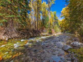 Experience the beauty of autumn with this stunning property featuring a crystal-clear river flowing through vibrant fall foliage.