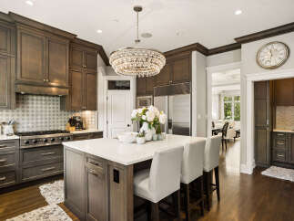 Experience luxury in this stunning kitchen, featuring custom dark wood cabinetry and a spacious quartz island perfect for entertaining.