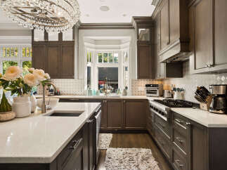 Experience luxury in this stunning kitchen, featuring custom dark wood cabinetry and gleaming quartz countertops.