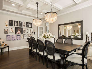 This elegant dining room features a large dark wood table surrounded by black cane-backed chairs, perfect for hosting.