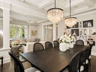 Experience elegant dining in this sophisticated space, featuring a dark wood table set for intimate gatherings and illuminated by two stunning crystal chandeliers.